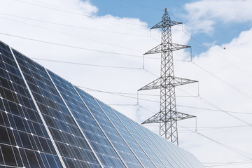 Solarzelle zur &ouml;kologischen Energiegewinnung und Strommasten als Energie Infrastruktur im Hintergrund