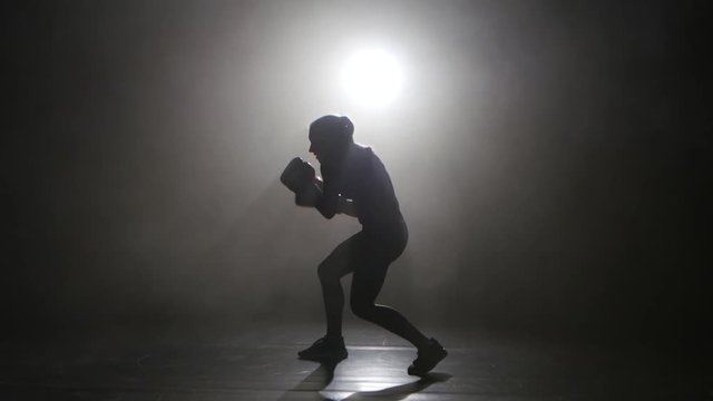 Champion kickboxer smoke evades counter punches. Silhouette. Black background . Side view