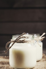 Fresh cow milk or cream in glass bottles, rustic style, vintage wood background