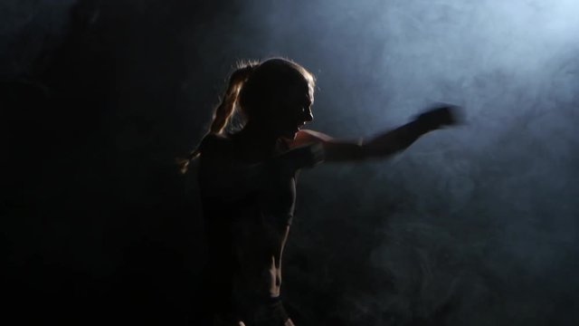 Champion boxer sends the punches. Silhouette. Black background. Side view