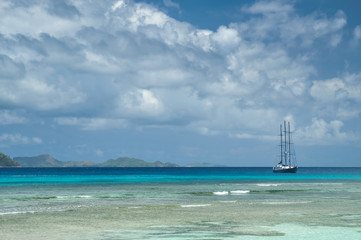 Lonely sailing ship next to amazing reef under turquoise-water