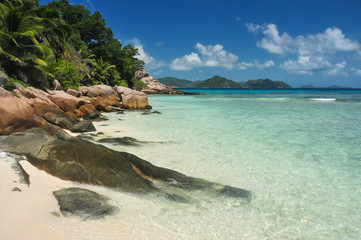 Granite stones on tropical white-sand beach next to turquoise water