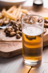 Beer, fried potatoes, mussels, lemon on parchment side view