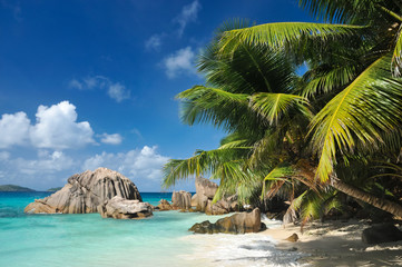 Fototapeta na wymiar Granite stones on tropical white-sand beach next to turquoise water