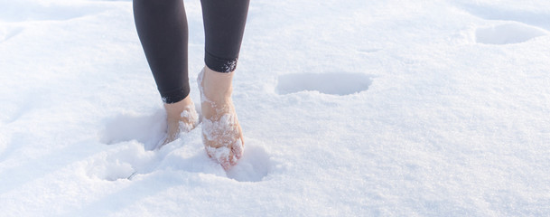 Girl barefoot on white cold snow in winter. Quenching tempering harding health concept. Female feet...