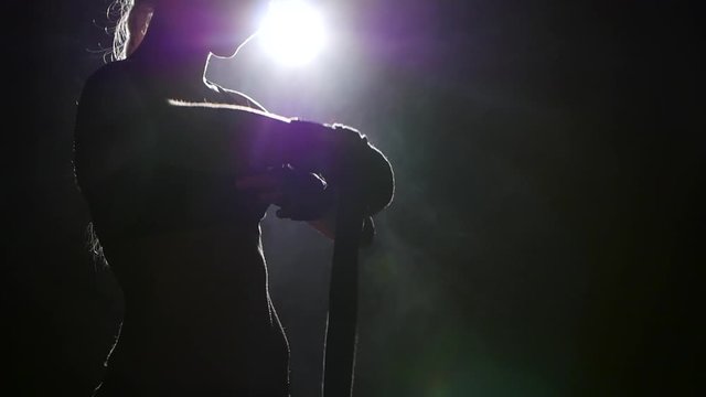 Boxer pulls in his arms protective bandages. Silhouette. Black background . Side view. Close up. Slow motion