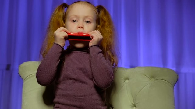 Little cute girl playing harmonica