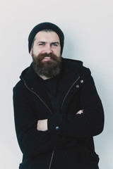 bearded happy brutal caucasian man in black jacket and hat