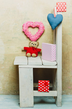 valentines day hearts, bear toy, present boxes on wooden chair