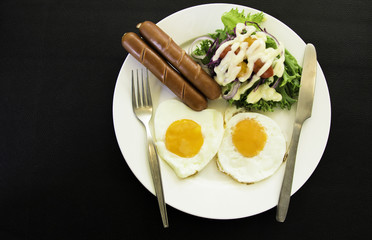 Breakfast with bacon, fried eggs on a white plate, vegetable salad on background, Morning Food for Traveler.