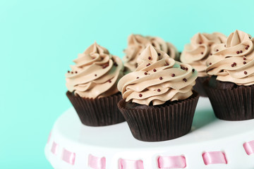 Tasty cupcakes on cake stand on green background