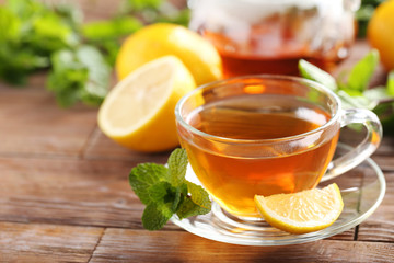 Cup of tea with mint and lemon on brown wooden table