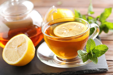 Cup of tea with mint and lemon on brown wooden table