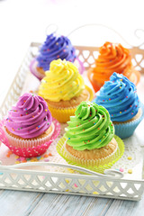 Tasty cupcakes in tray on a white wooden table