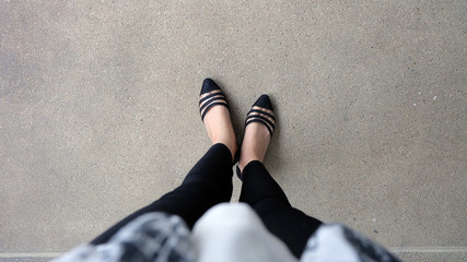 Woman Wearing Black Slippers Standing on Ground Background Great for Any Use.