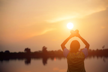 A woman holding a sunset heart