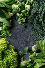 Photo sur Aluminium Légumes Variété de salades de légumes verts crus, laitue, bok choy, maïs, brocoli, chou de Milan comme cadre sur fond de texture de pierre noire. Vue de dessus, espace pour le texte