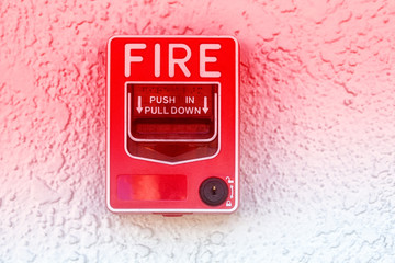 Red fire alarm switch at cement wall