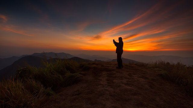 Silhouette of a man taking picture in the sunset