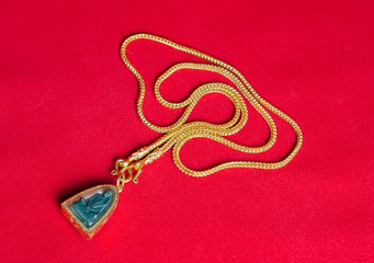 Gold necklace 96.5 percent Thai gold grade with Buddha and gold frame pendant isolated on red flannel cloth background