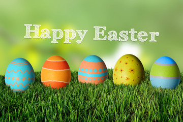 Inscription Happy Easter and painted colorful eggs in the grass.