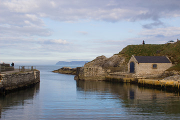 Fototapeta na wymiar The small harbor at Ballintoy on the North Antrim Coast of Northern Ireland with its stone built boathouse on a day in spring/