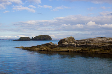 Fototapeta na wymiar The rocky entrance to the harbor at Ballintoy on the North Antrim Coast of Northern Ireland with its stone built boathouse on a day in spring