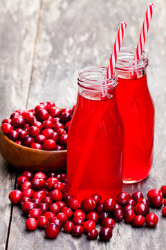 Organic  cranberry juice in bottles with berries on wooden background