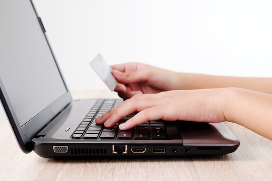 Woman hands holding credit card and typing labtop on table background, selective focus, shopping online concept, business and technology