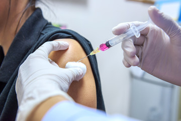 Close-up hands,nurses are vaccinations to patients using the syringe.Doctor vaccinating women in...