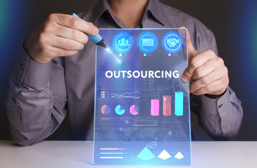 Business, Technology, Internet and network concept. Young businessman working on a virtual screen of the future and sees the inscription: Outsourcing