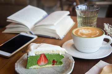 coffee cup and tasty cake relax time book and mobile phone on table in coffee shop