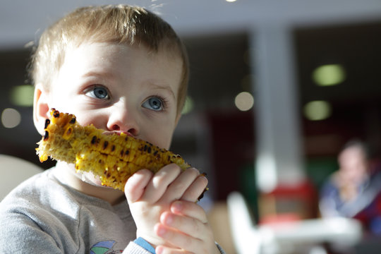 Kid eating grilled cob corn