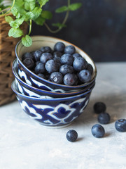Three stacked ceramic bowls with ripe blueberries on a gray table
