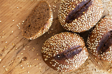 Black bread with sesame seeds on a wooden background