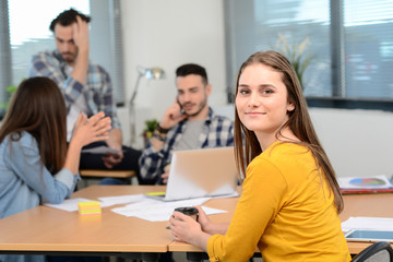 portrait of young woman in casual wear working in a creative business startup company office with coworker people in background