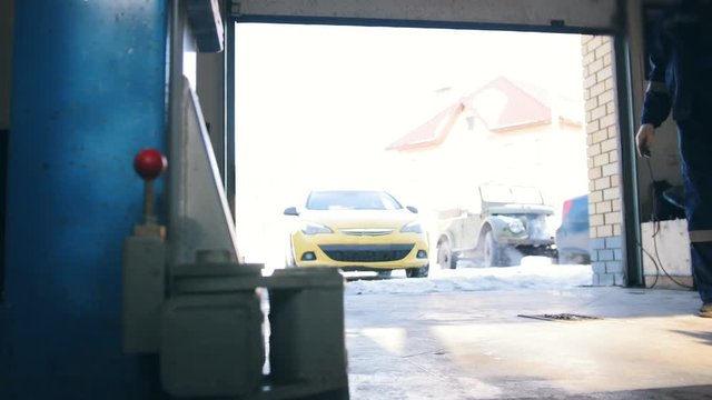 Car service work - yellow car drives to garage at sunny winter day