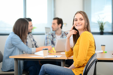 Fototapeta premium portrait of young woman in casual wear working in a creative business startup company office with coworker people in background