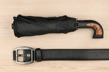 Umbrella and genuine leather strap lie on a wooden surface