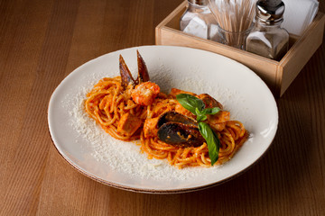 Pasta with seafood on a white plate on a wooden table