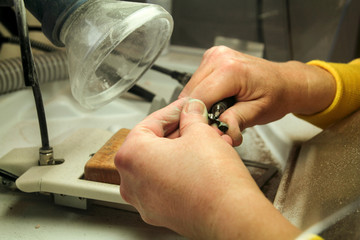 Hands of dental technician processing metal oral prosthesis