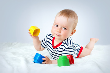 Nine month old baby lying in the bed on white blanket