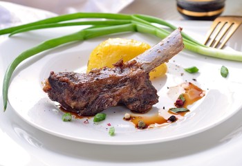 Pork rib and fried potatoes on white plate