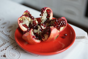 Ripe large pomegranate on a red plate on a table