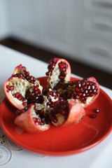 Ripe large pomegranate on a red plate on a table
