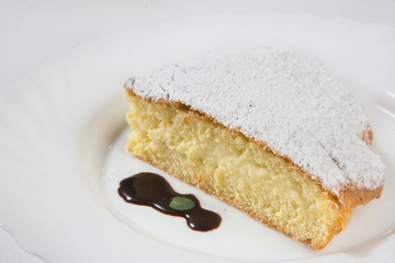 slice of lemon cake sprinkled with powdered sugar and melted chocolate topping