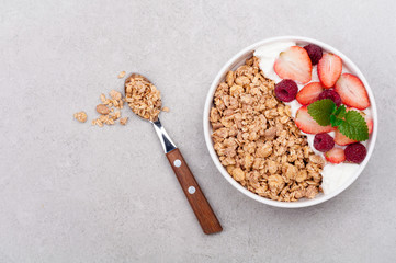 Healthy breakfast with granola, berries and yogurt on gray background. Healthy eating oatmeal. Top view. Copy space