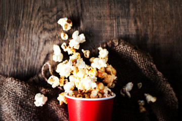Fresh Popcorn in a red cardboard box on the wooden table, Cinema concept.