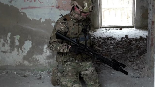 A military man with a weapon is ambushed in an abandoned building