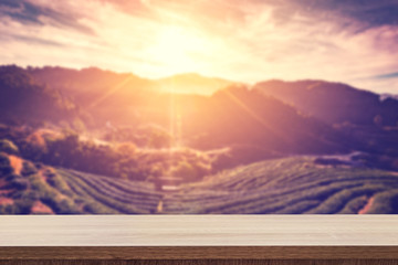 Fototapeta na wymiar Empty wooden table for product placement or montage and blurred tea field and sunrise vintage.